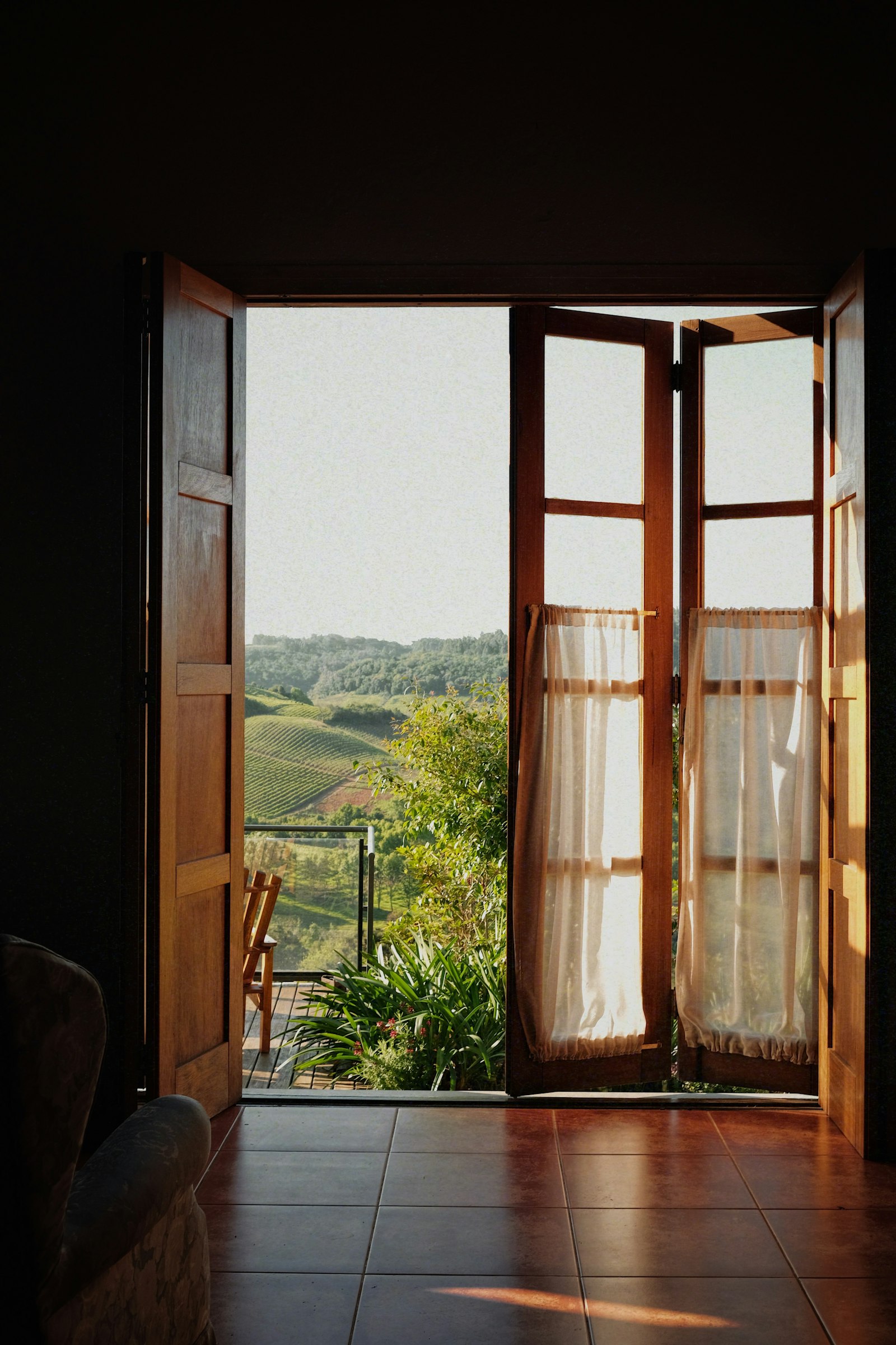 Open wooden doors revealing a green rolling landscape