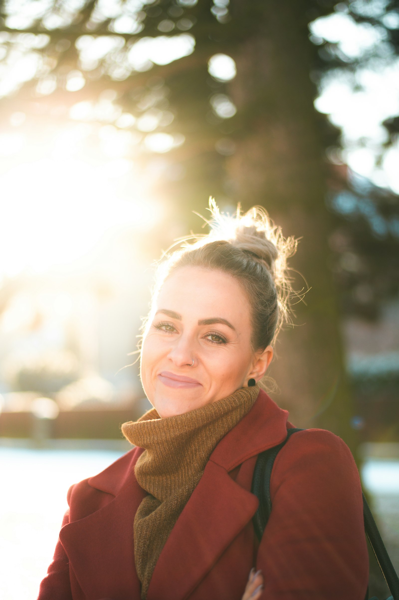 Maya Ellison smiling in low golden sunlight, wearing a red coat